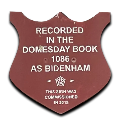 Biddenham Village Sign, reading the words "Recorded in the Domesday Book 1086 as Bidenham". The sign was commissioned in 2015.